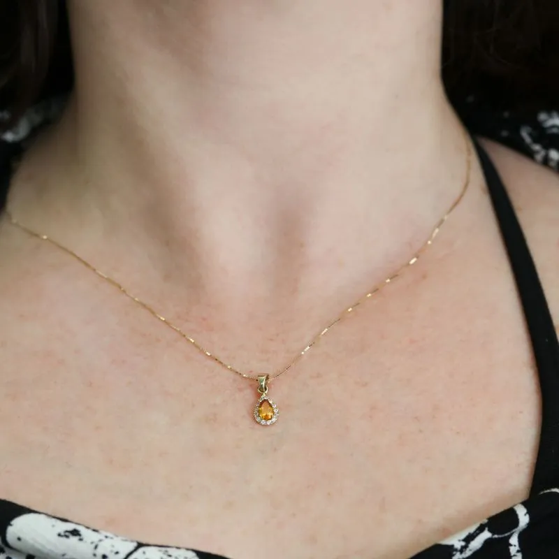 A drop-shaped halo pendant with a citrine stone on a 14K gold chain.